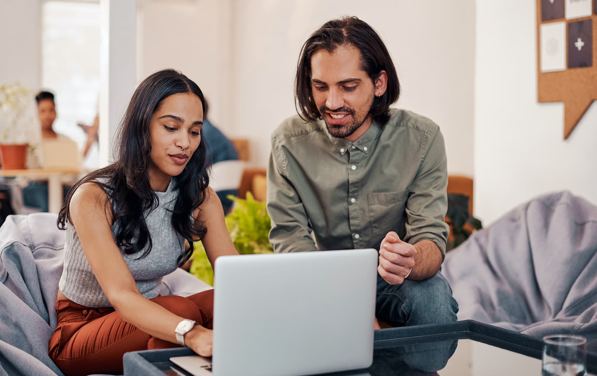 A woman and a man looking at a laptop together in an office lounge