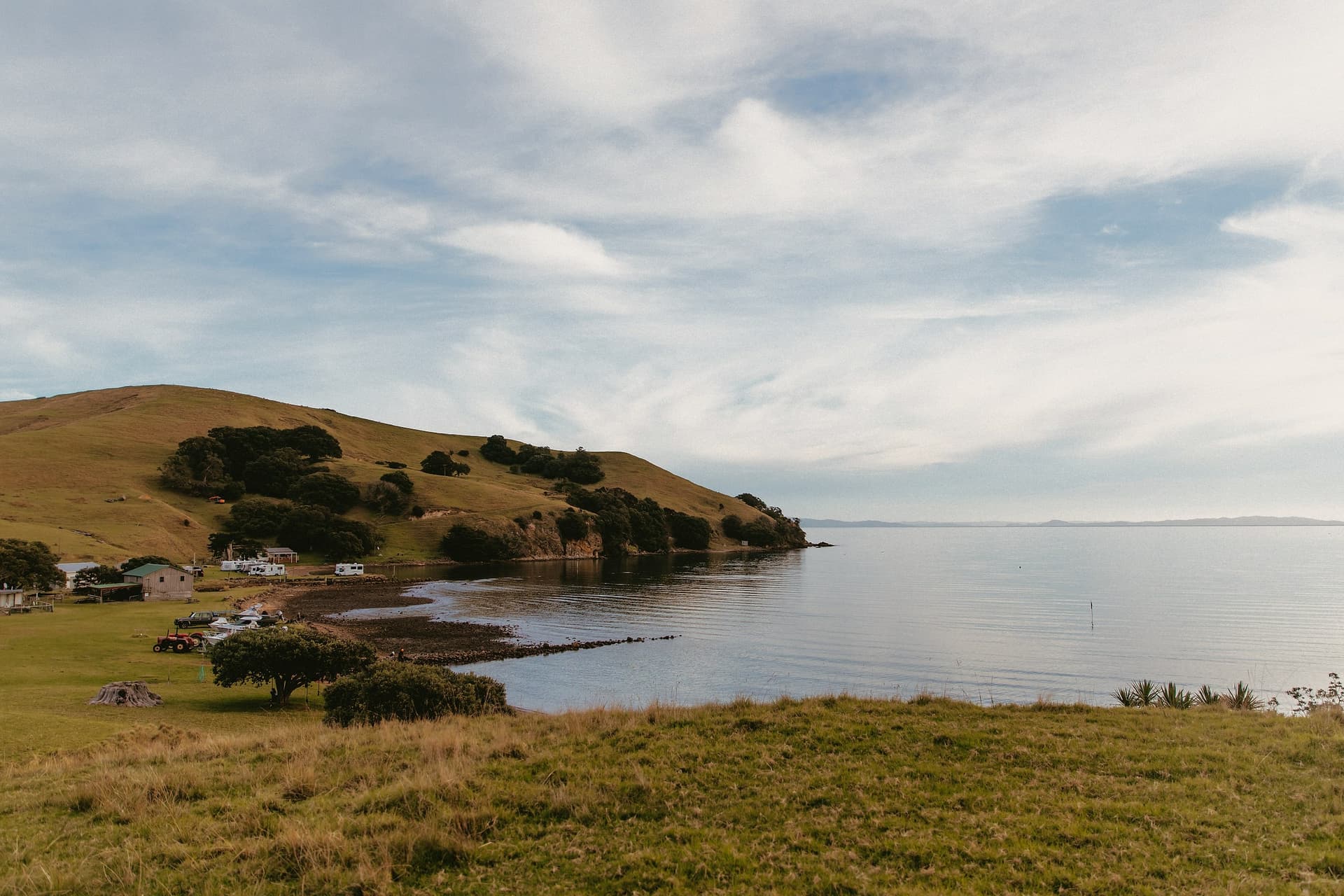 A quiet bay with a grassy headland and a few homes along the shore